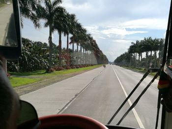 Road amidst trees against sky seen through car windshield