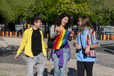 Young diverse friends walking on the street with the lgbt rainbow flag.