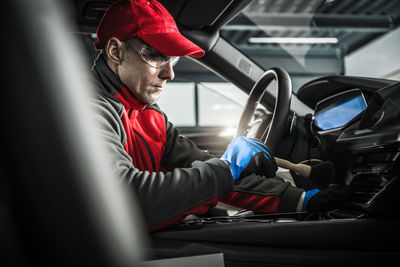 Side view of man sitting in car