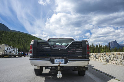 Vehicles parked on road against sky in city