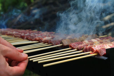 Close-up of person preparing food on barbecue grill