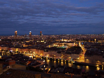 High angle view of illuminated cityscape against cloudy sky