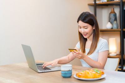 Young woman using mobile phone while sitting at home