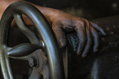 Cropped hands of worker holding work tool at workshop