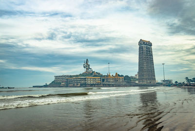 View of building by sea against cloudy sky