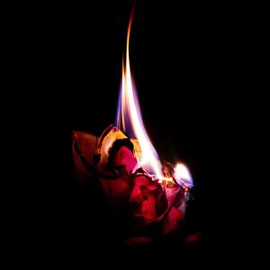 Close-up of burning candle against black background