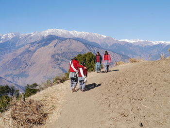 Rear view of woman standing on mountain against sky