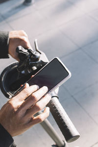 Close up of a young man using an app on his phone to get around the city on an electric scooter.