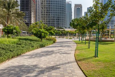 Footpath in park against buildings in city