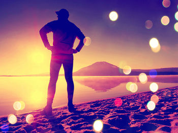 Rear view of man standing by sea against sky at night