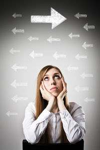 Portrait of young woman looking away against wall