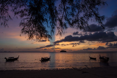 Silhouette boats in sea against sky during sunset