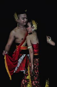 Full length of shirtless young woman standing against black background