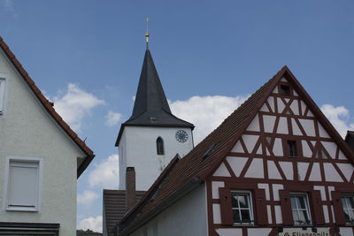 Low angle view of houses and clock tower against sky