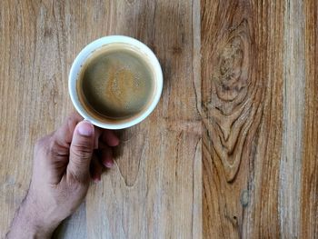 Hand holding coffee cup on table