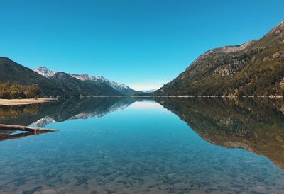 Scenic view of lake and mountains against clear blue sky