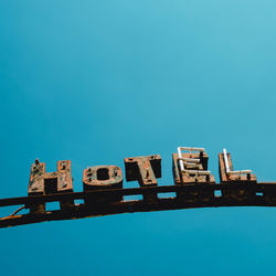 Low angle view of old hotel sign against clear blue sky