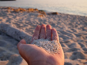 Close-up of hand holding sand at beach