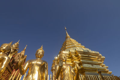 Low angle view of statue against temple building against clear sky