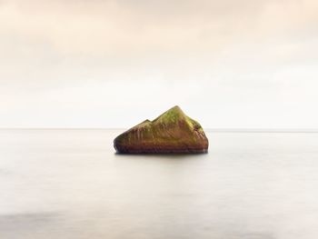 Alone stone in smooth sea. beautiful seascape with low lightt. sea and rock at sunset. long exposure