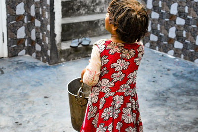 Rear view of girl holding bucket