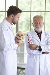 Male doctors examining human skulls in hospital