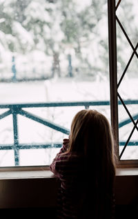 Rear view of woman looking through window