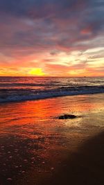 Scenic view of sea against dramatic sky during sunset