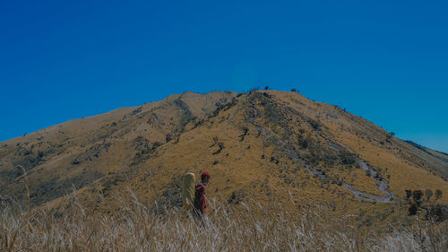 Man standing on mountain against clear blue sky