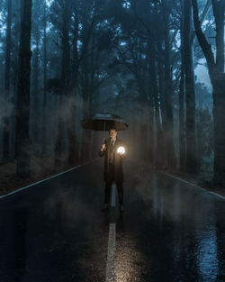 Man standing on wet road in forest during rainy season