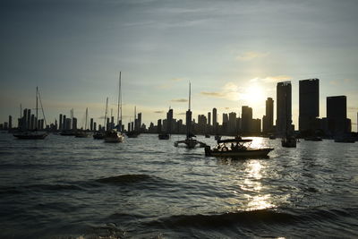 Boats sailing in sea against sky during sunset