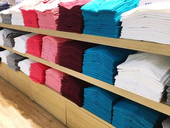 Colorful clothes in shelves for sale at store