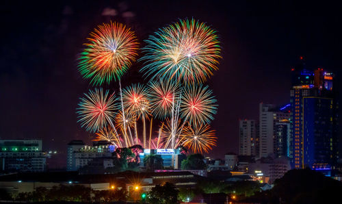 Firework display in city against sky at night