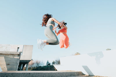 Low angle view of woman standing on staircase against clear sky