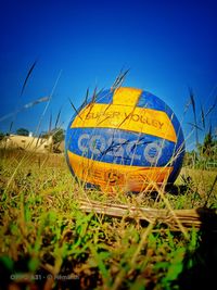 Close-up of yellow umbrella on field against blue sky