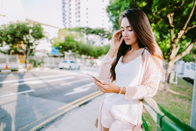 Young woman using mobile phone in city