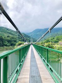 Footbridge against cloudy sky