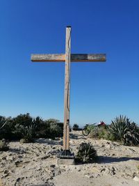 Cross on land against clear blue sky