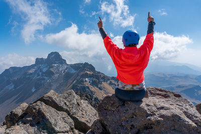 Rear view of man standing on mountain against sky