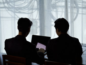 Rear view of man and woman sitting at home