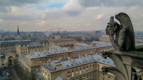 Statue in city against cloudy sky