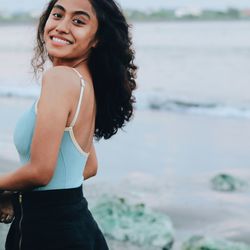 Portrait of smiling young woman standing against sea