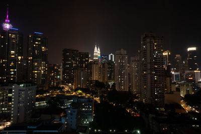 Illuminated buildings in city against sky at night