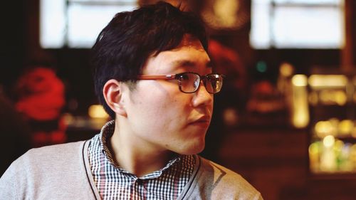 Close-up of young man looking away while sitting at cafe