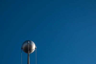 Low angle view of telephone pole against clear blue sky