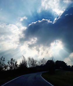 Road by trees against sky