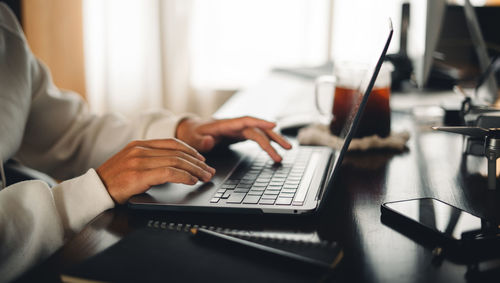 Midsection of man using laptop on table