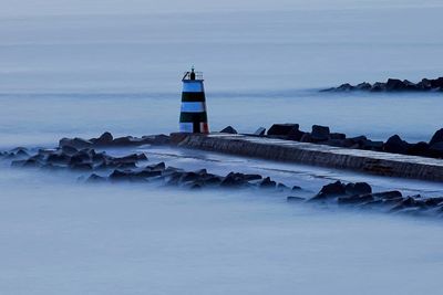 Lighthouse by sea against sky