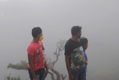 Rear view of people standing in foggy weather