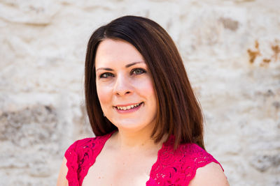 Portrait of smiling woman against wall